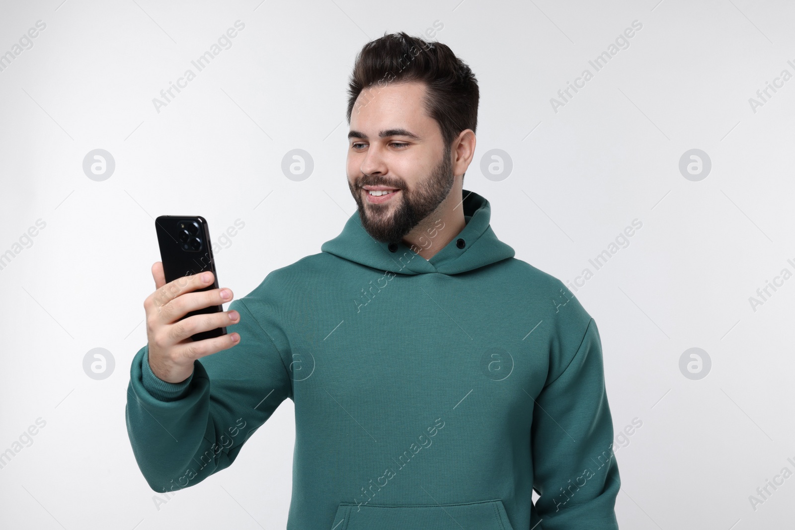 Photo of Happy young man using smartphone on white background