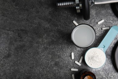 Photo of Amino acid shake, powder, pills and dumbbell on grey table, flat lay. Space for text
