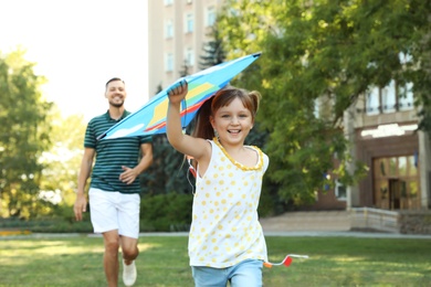 Father and his cute child playing with kite in green park on sunny day. Happy family