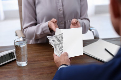 Photo of Man giving bribe money to woman at table, closeup