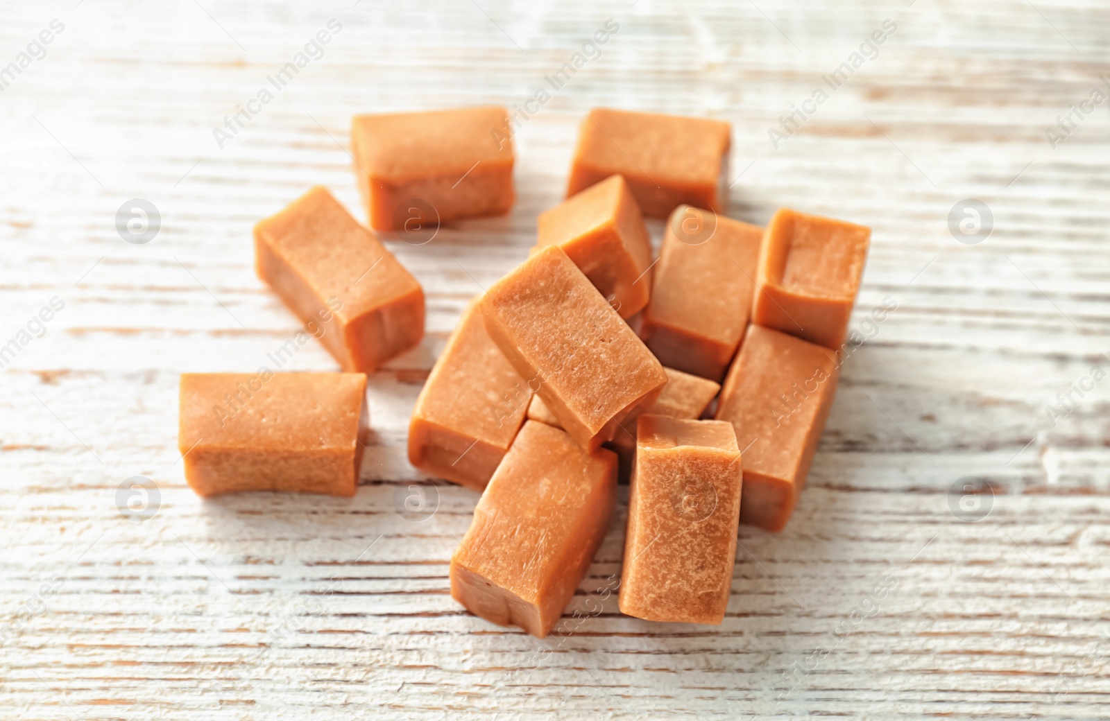 Photo of Delicious caramel candies on wooden background