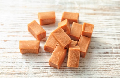 Photo of Delicious caramel candies on wooden background