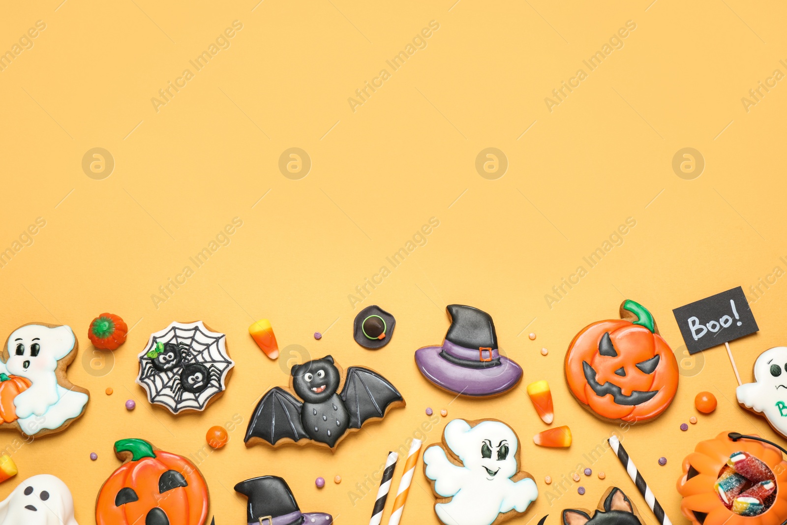 Photo of Flat lay composition with decorated gingerbread cookies on yellow background, space for text. Halloween celebration