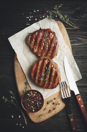 Image of Delicious beef medallions served on black wooden table, flat lay. Food photography  