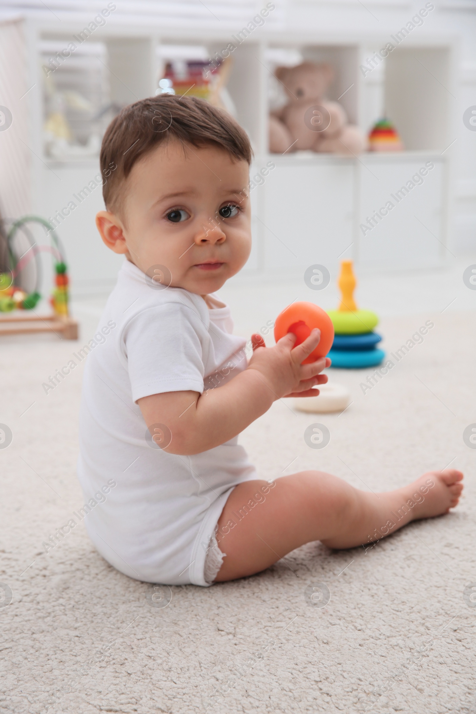 Photo of Cute baby boy playing with toy on floor at home