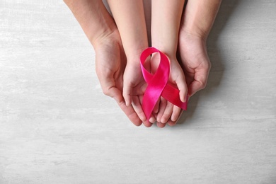 Photo of Woman and girl holding pink ribbon on grey background, top view with space for text. Breast cancer awareness