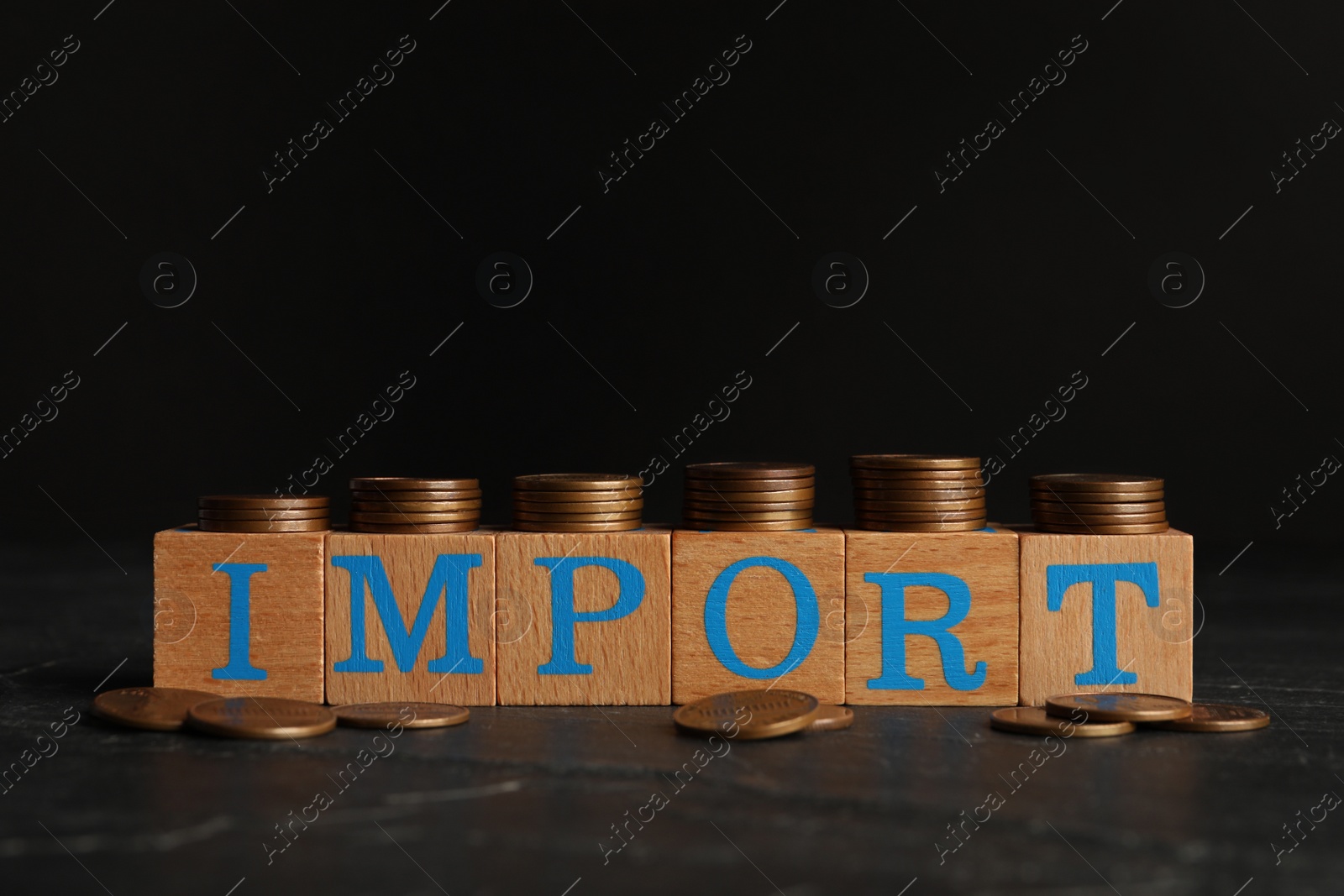 Photo of Word Import made of wooden cubes with letters and coins on black table