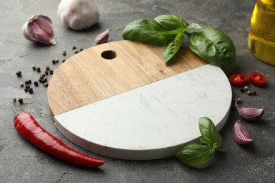 Photo of Cutting board, basil, pepper, chili peppers and garlic on grey table. Space for text