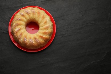 Photo of Delicious freshly baked sponge cake on black table, top view. Space for text