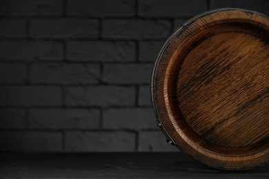 Photo of One wooden barrel on table near brick wall, closeup. Space for text