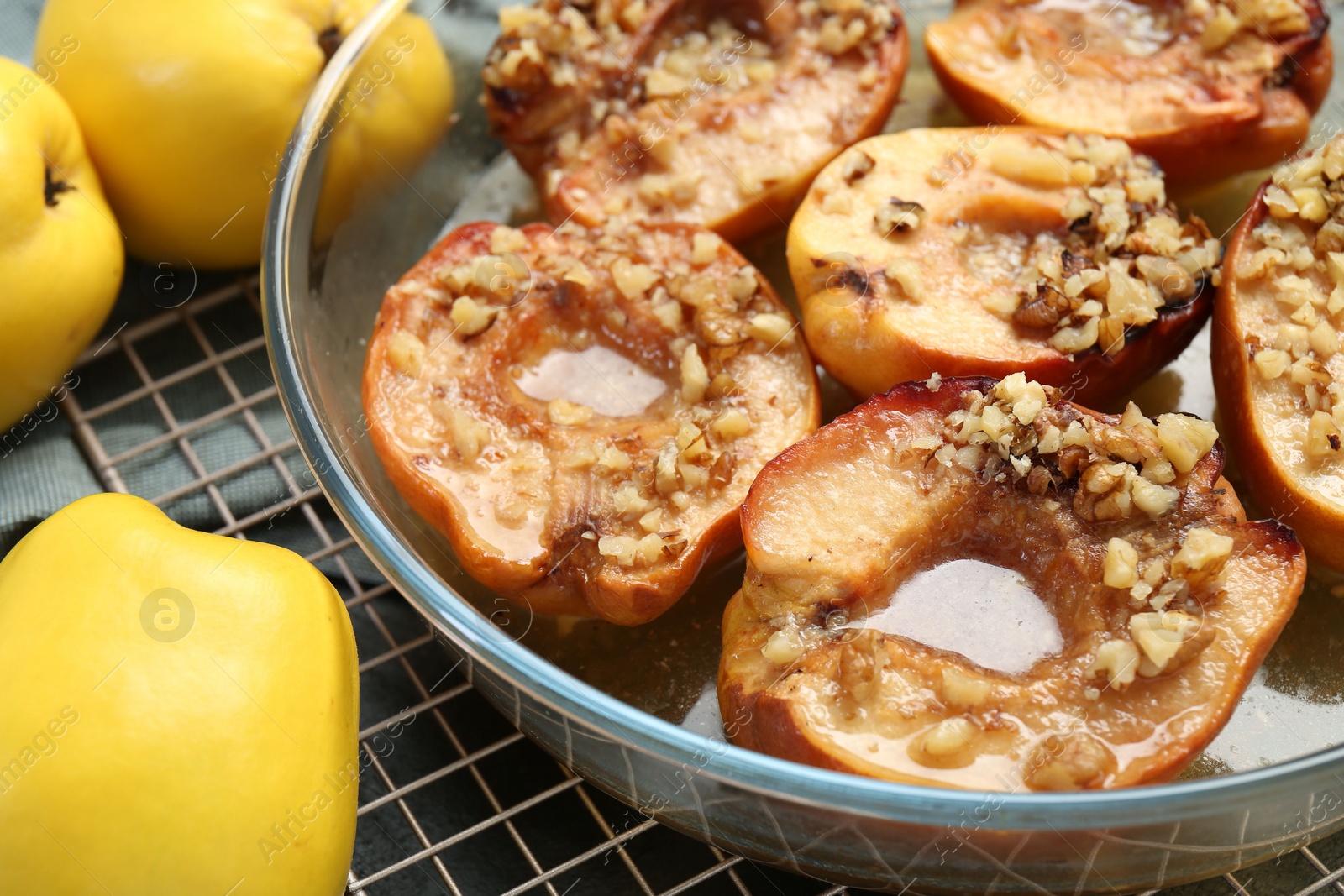 Photo of Tasty baked quinces with walnuts and honey in bowl on table, closeup