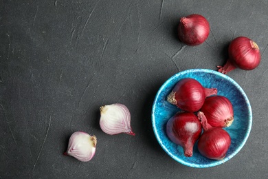 Bowl with ripe red onions on table, top view