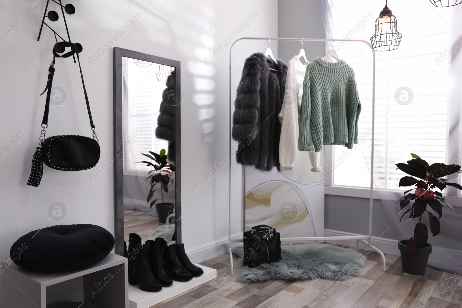 Photo of Stylish warm clothes on rack in dressing room interior