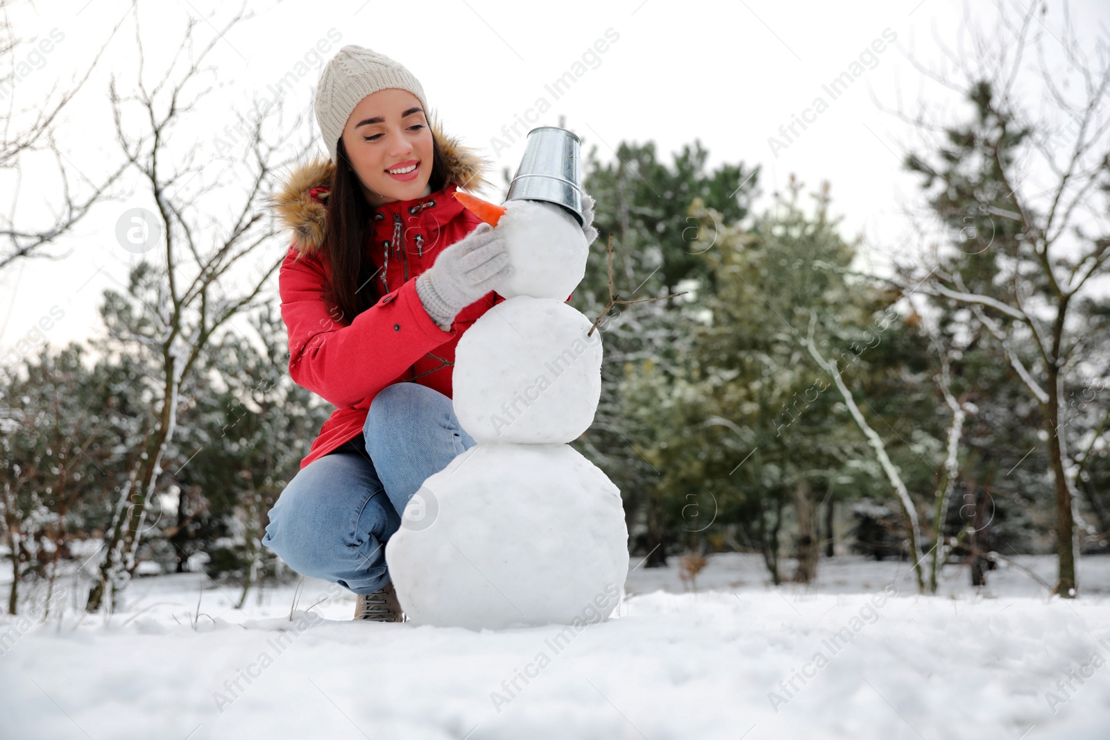 Photo of Young woman making snowman outdoors on winter day. Space for text