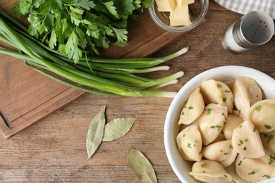 Photo of Delicious cooked dumplings with herbs on wooden table, flat lay