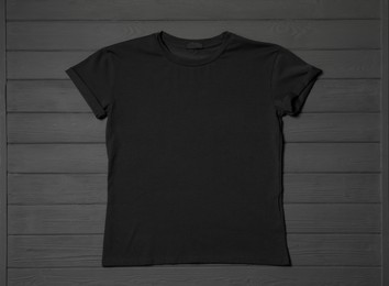 Stylish black T-shirt on gray wooden table, top view