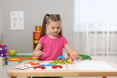 Photo of Motor skills development. Girl playing with colorful wooden arcs at white table in kindergarten, space for text