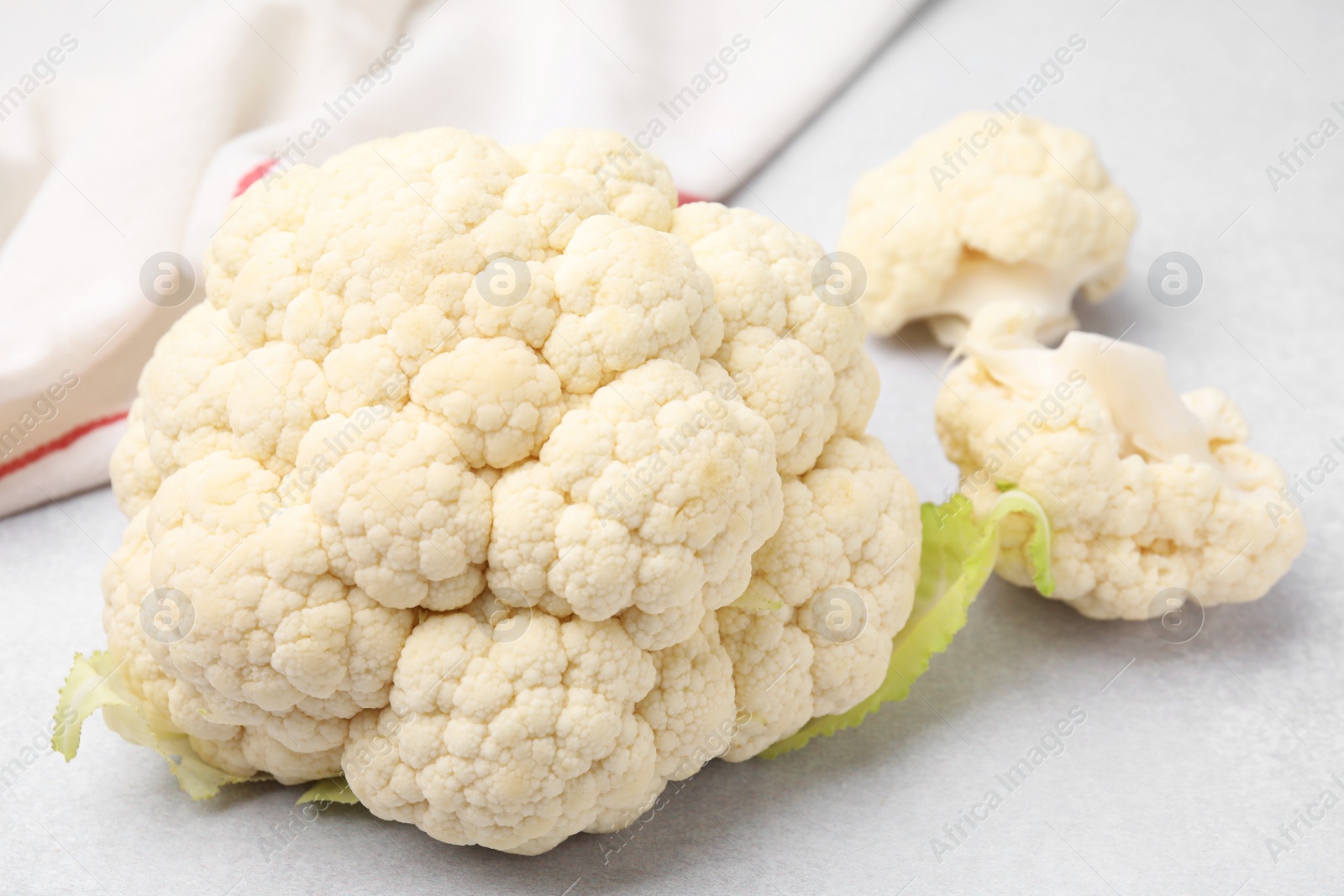 Photo of Cut fresh raw cauliflower on light grey table, closeup