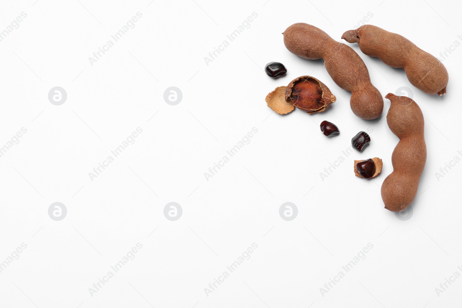 Photo of Ripe tamarinds on white background, flat lay. Space for text