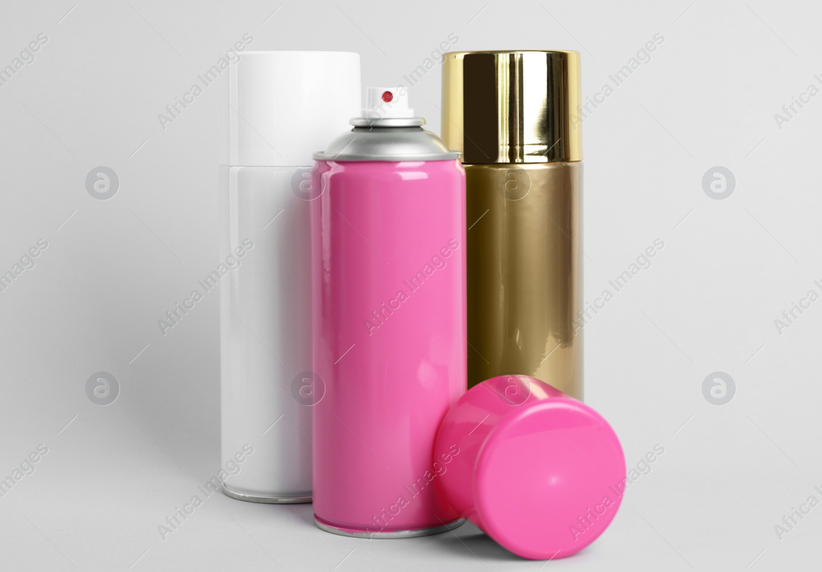 Photo of Colorful cans of spray paints on light grey background