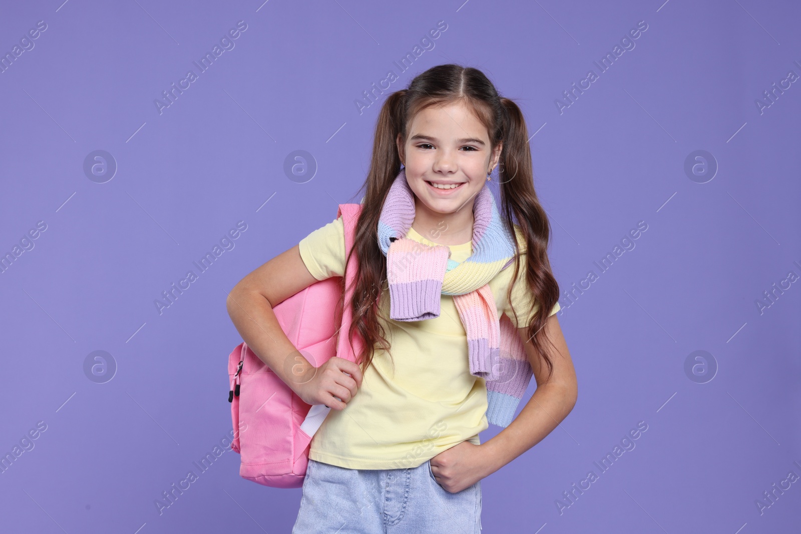 Photo of Back to school. Cute girl with backpack on violet background