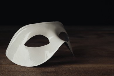 Photo of White theatre mask on wooden table, closeup. Space for text