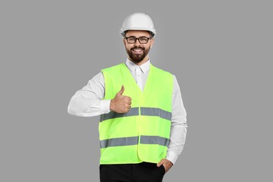 Photo of Engineer in hard hat showing thumb up on grey background