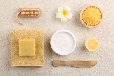 Flat lay composition with moisturizing cream in open jar and other body care products on light textured table