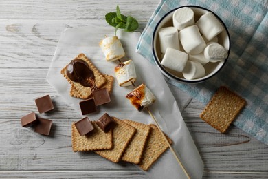 Photo of Ingredients for delicious sandwich with roasted marshmallows and chocolate on white wooden table, flat lay