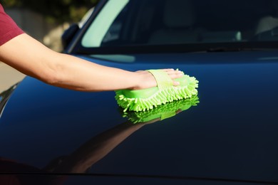 Photo of Man cleaning car hood outdoors, closeup view