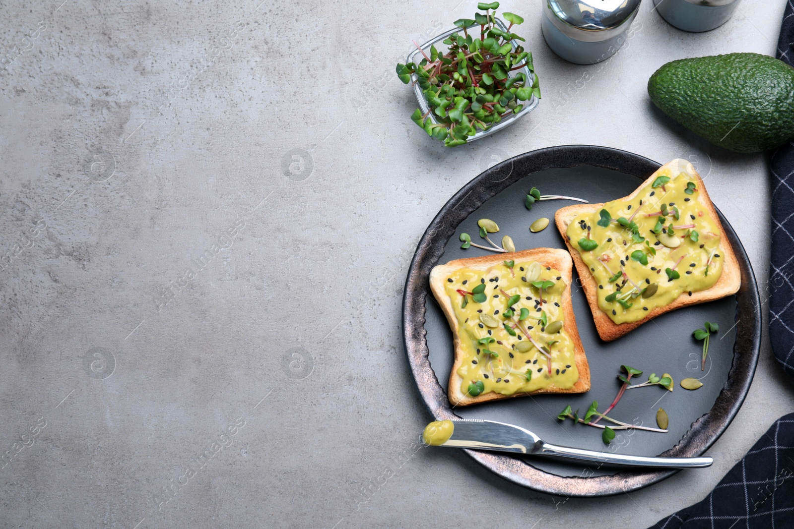 Photo of Delicious sandwiches with guacamole, seeds and microgreens on grey table, flat lay. Space for text