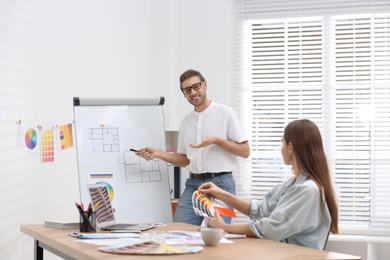 Photo of Professional interior designer near whiteboard and colleague in office