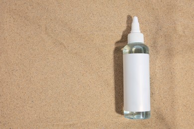 Bottle with serum on sand, top view and space for text. Cosmetic product