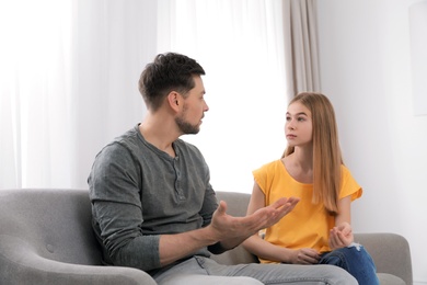 Photo of Father talking with his teenager daughter at home