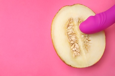 Photo of Half of melon and purple vibrator on pink background, flat lay with space for text. Sex concept