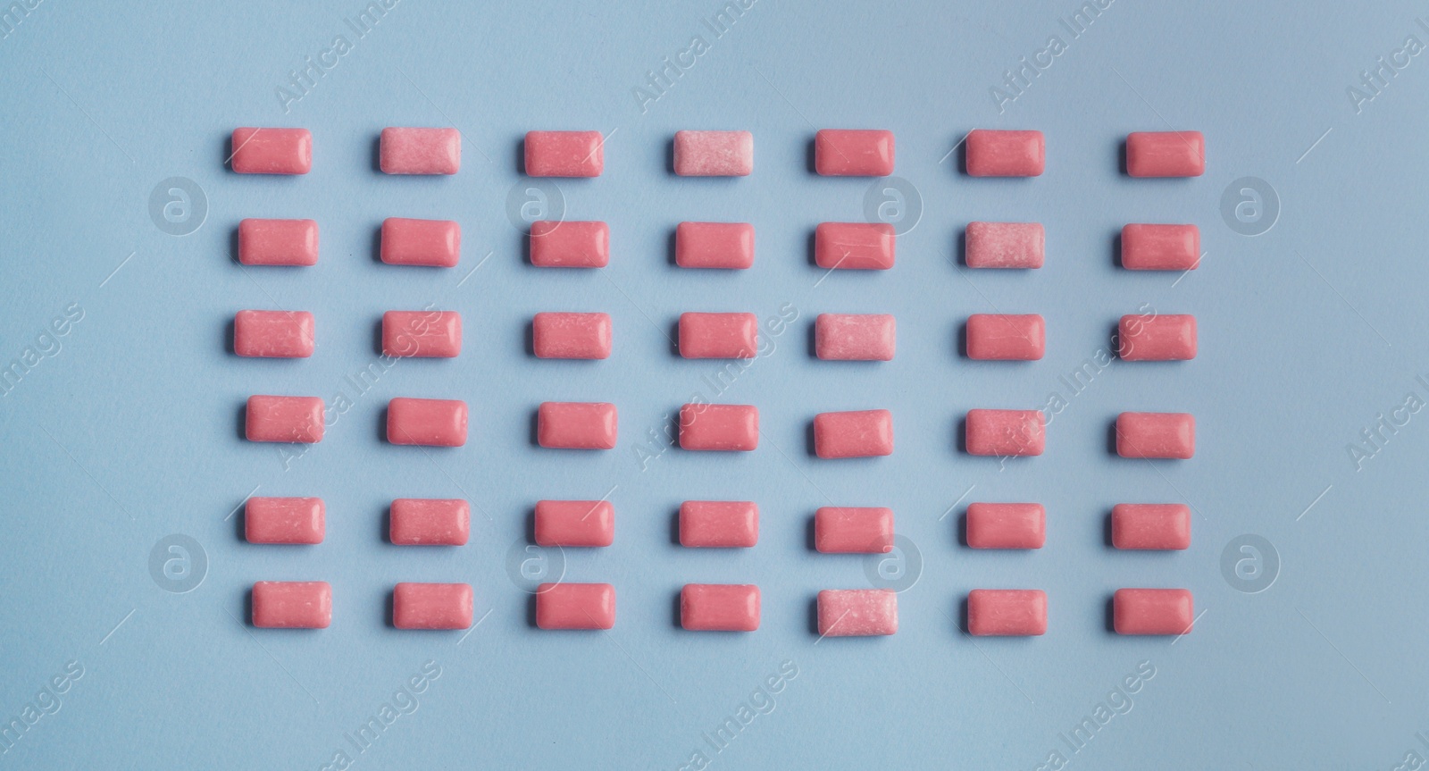 Photo of Many sweet chewing gums on light blue background, flat lay