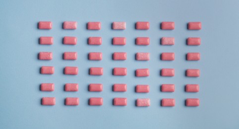 Photo of Many sweet chewing gums on light blue background, flat lay