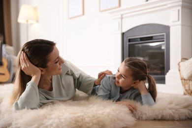 Photo of Happy woman with her daughter resting near fireplace at home