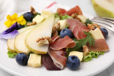 Photo of Tasty salad with brie cheese, prosciutto, walnuts and pear on white plate, closeup