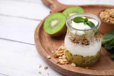 Photo of Delicious dessert with kiwi, yogurt and muesli on wooden board, closeup. Space for text