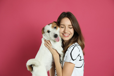 Photo of Young woman with her cute Jack Russell Terrier on pink background. Lovely pet