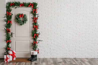 Photo of Stylish hallway interior with decorated door and Christmas gifts, space for text