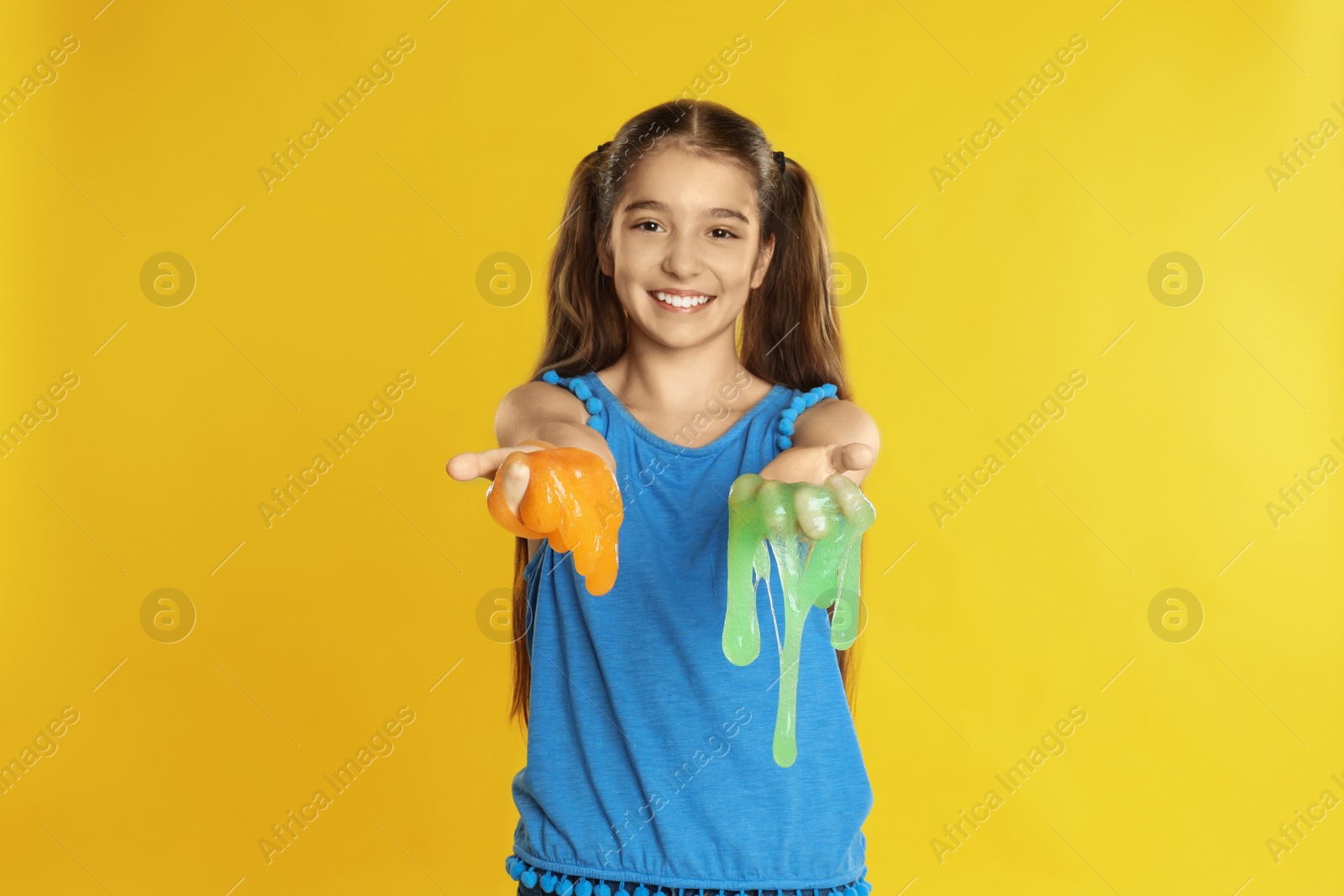 Photo of Preteen girl with slime on yellow background