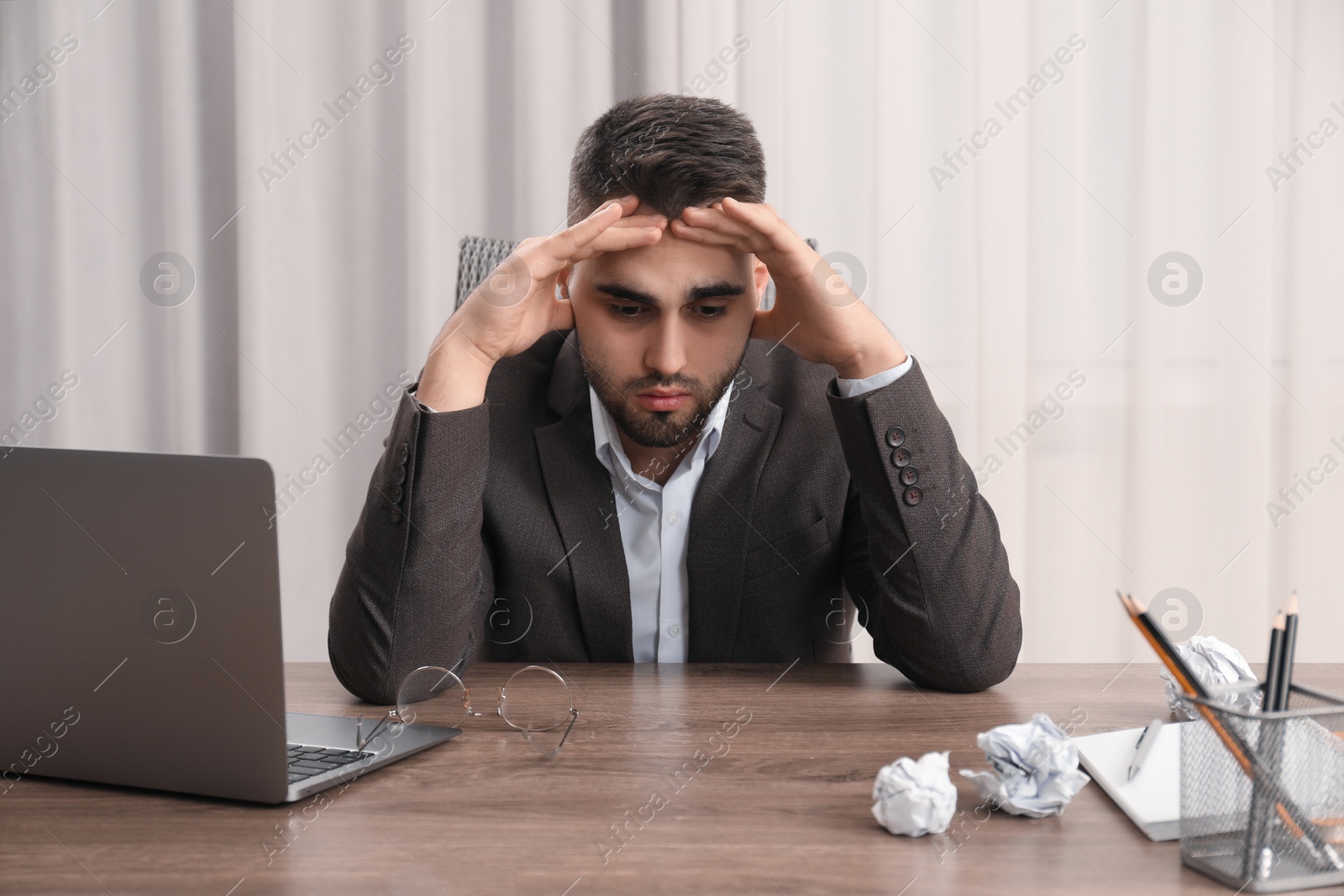 Photo of Tired sad businessman sitting at table in office