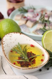 Photo of Tasty fish marinade with rosemary and products on light tiled table, closeup