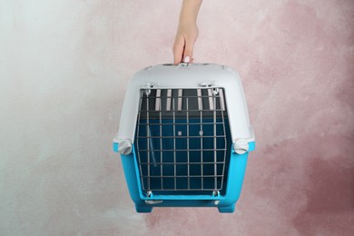 Photo of Woman holding light blue pet carrier against pink wall, closeup