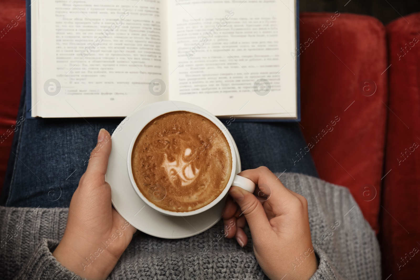 Photo of Woman with cup of coffee reading book at home, top view