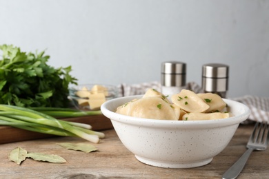 Photo of Bowl of delicious cooked dumplings on wooden table