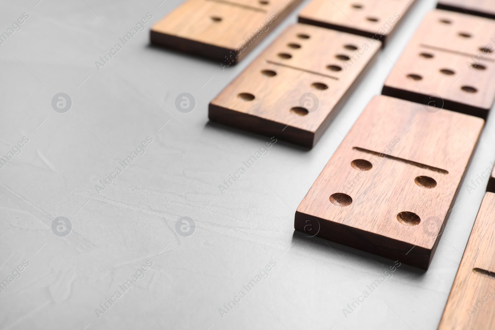 Photo of Set of wooden domino tiles on grey table, closeup. Space for text