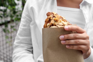 Photo of Woman with delicious croissant outdoors, closeup view